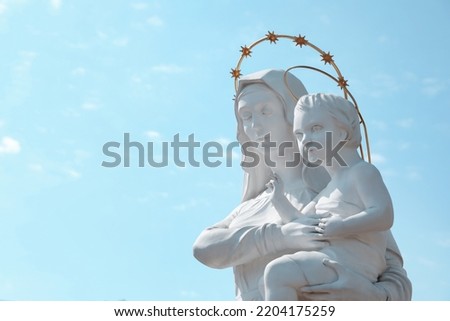 Beautiful statue of Virgin Mary and baby Jesus against blue sky. Space for text