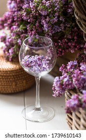 Beautiful still life, spring card. Purple lilac lies in a glass, surrounded by flowers and wicker baskets.