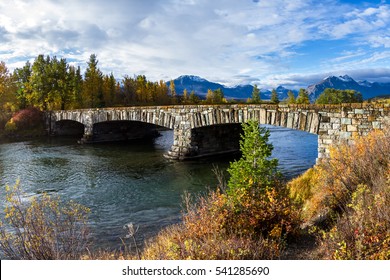 Beautiful Stone Bridge Entering Glacier National Park In Montana From The East Entrance With Golden Vegetation And Tall Peaks In The Background