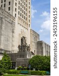 beautiful stone statues in front of the Louisiana State Capitol building surrounded by lush green trees and plants, blue sky and clouds in Baton Rouge Louisiana USA