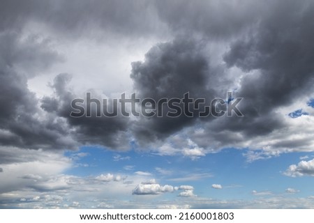 Beautiful storm sky, dark grey and white cumulus clouds on blue sky background texture, thunderstorm