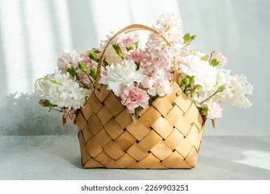 Beautiful straw bag with seasonal flowers of hyacinth and carnation blossom Stock Photo