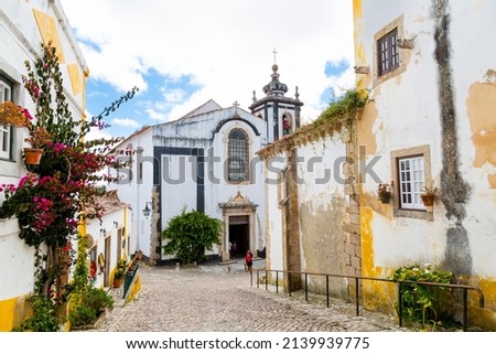 Beautiful street of Óbidos with Saint Peter church at the background