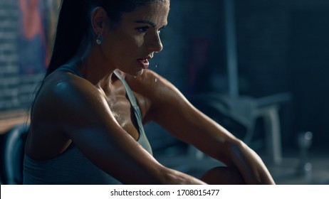 Beautiful Strong Fit Brunette in Sport Top and Shorts in a Loft Industrial Gym with Motivational Posters. She's Catching Her Breath after Intense Fitness Training Workout. Sweat All Over Her Face. - Powered by Shutterstock