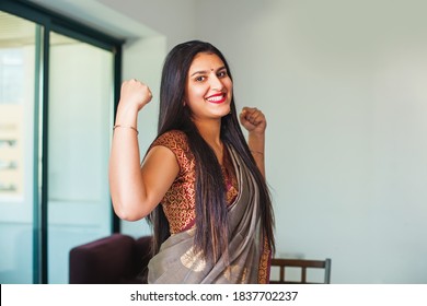 Beautiful strong Indian woman showing muscles while wearing a saree. Girl power concept