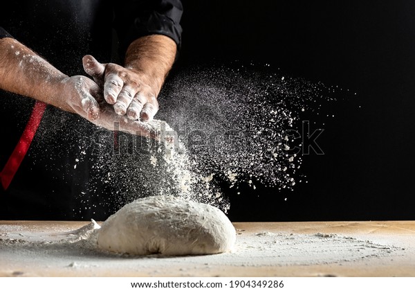 Beautiful and strong\
men\'s hands knead the dough make bread, pasta or pizza. Powdery\
flour flying into air. chef hands with flour in a freeze motion of\
a cloud of flour\
midair.