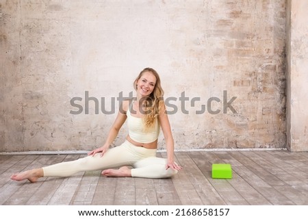 beautiful strong muscular woman doing stretching with blocks in gym. Healthy young adult woman in light sportswear stretch alone. Fit thin gimnast doing acrobatics indoors, training	