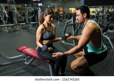 Hermosa mujer fuerte haciendo ejercicios de levantamiento de pesas con pesas de campanilla con entrenador de fitness masculino