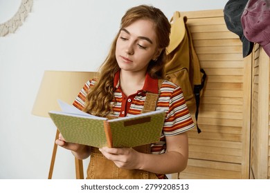 Beautiful student absorbs knowledge while reading in a warm, inviting space with minimal decor.
