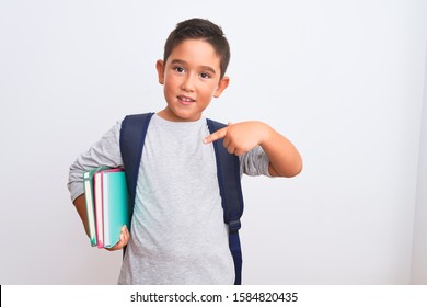 Beautiful student kid boy wearing backpack holding books over isolated white background very happy pointing with hand and finger - Shutterstock ID 1584820435