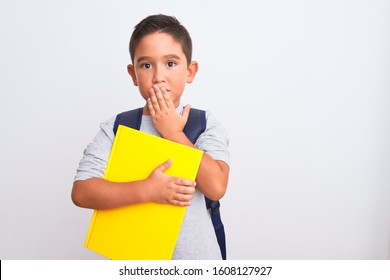 Beautiful Student Kid Boy Wearing Backpack Holding Book Over Isolated White Background Cover Mouth With Hand Shocked With Shame For Mistake, Expression Of Fear, Scared In Silence, Secret Concept