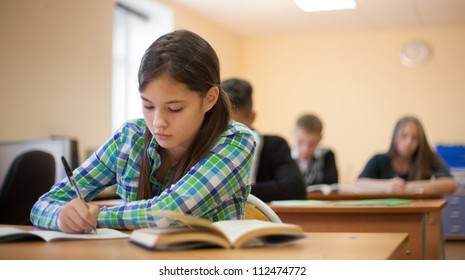 Beautiful student writing lecture on the background of her classmates - Powered by Shutterstock