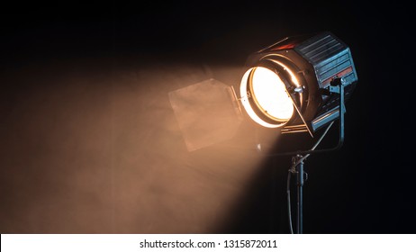 Beautiful Studio Light For A Movie And TV Show On A Dark Background With Smoke. A Ray Of Light Penetrates The Smoke And Darkness. Professional Light For The Production Of Cinema.