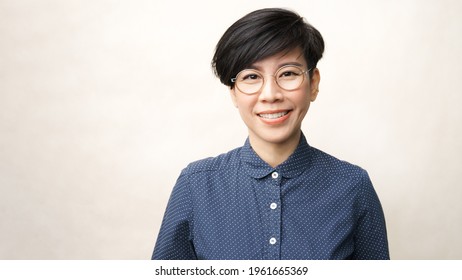 Beautiful Studio Portrait Of A Smart Look Asian Middle Aged Woman With Round Eye Glasses In Casual, She Looking To Camera And Smile With Satisfied. Progressive Lens, Eyewear, 40s, Short Hairstyle.