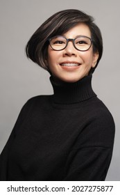 Beautiful studio portrait of a stylish 40s asian executive woman with eye glasses in black turtleneck top smiling with confident and satisfy. Model, Eyewear, Perfect Ageing Skin, Teeth, ShortHairstyle