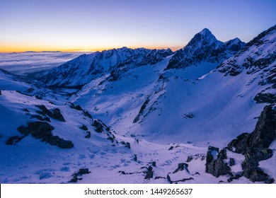 Beautiful and stunning panorama view of a winter alpine like mountain landscape at sunset or sunrise. Adventure climb or mountaineering in High Tatras, Slovakia. Snow covered peaks and summits.