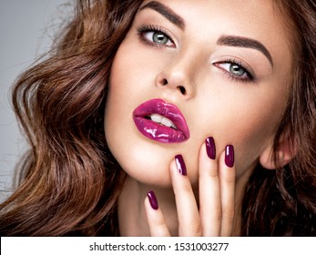 Beautiful and stunning woman with bright purple lipstick on lips and fingernails.  Young caucasian gorgeous adult girl. Model. Closeup woman's portrait. Vivid make-up. Sexy female. 