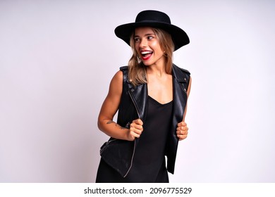 Beautiful Stunning Woman With Red Full Lips, Elegant Casual Black Dress, Hat And Leather Vest Posing On White Background. Free Spirit, Rock N Roll Style, Having Fun.