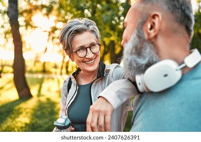 Beautiful stylish cheerful sincere carefree happy gray-haired senior woman in glasses and sportswear rests her hand on her friend and laughs while talking outdoors.Morning jogging. - Powered by Shutterstock