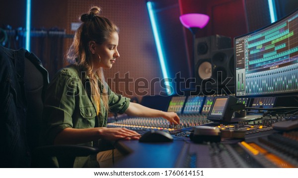 Beautiful, Stylish Female Audio Engineer and\
Producer Working in Music Recording Studio, Uses Mixing Board and\
Software to Create Cool Song. Creative Girl Artist Musician Working\
to Produce New Song