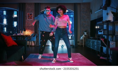 Beautiful Stylish Multiethnic Couple In Casual Outfits And Futuristic Neon Glowing Glasses, Dance And Enjoy Life At Home In Loft Apartment. Recording Funny Viral And Active Videos For Social Media.