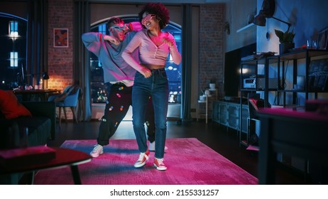Beautiful Stylish Multiethnic Couple in Casual Outfits and Futuristic Neon Glowing Glasses, Dance and Have a Party at Home in Loft Apartment. Recording Funny Viral and Active Videos for Social Media. - Shutterstock ID 2155331257