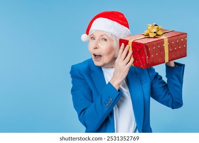 Beautiful stylish senior woman opening her Christmas gift. Unwrapping gift present boxed. Happy New Year Eve celebration! Guessing sharing presents, holiday shopping - Powered by Shutterstock