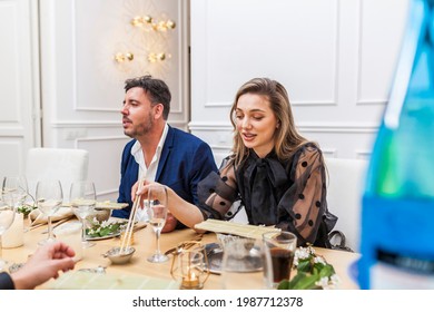 Beautiful Stylish Woman And Handsome Man Conversating And Eating Sushi With Friends At A Private Dinner Party 