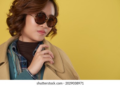 Beautiful Stylish Young Woman Taking On Warm Wool Coat, Isolated On Yellow Background