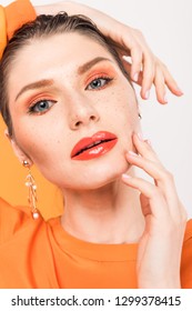 Beautiful Stylish Young Woman Touching Face And Looking At Camera With Tumeric On Background