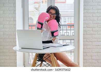 Beautiful Successful Businesswoman Sitting At Desk With Laptop Computer In Office Wearing Boxing Gloves. Strong Female Boss, Leader, Manager