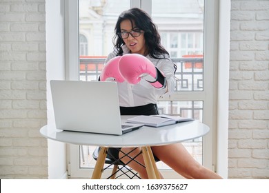 Beautiful Successful Businesswoman Sitting At Desk With Laptop Computer In Office Wearing Boxing Gloves. Strong Female Boss, Leader, Manager