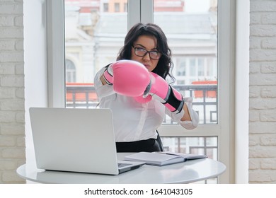 Beautiful Successful Businesswoman Sitting At Desk With Laptop Computer In Office Wearing Boxing Gloves. Strong Female Boss, Leader, Manager