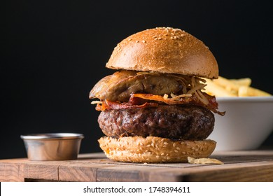 Ein schöner und köstlicher Rindfleischburger aus erstklassigem Rindfleisch mit knusprigem Speck und gebratenen Zwiebelringen lag auf einem Holzteller in Sesambrot