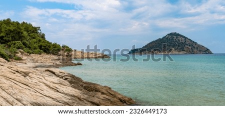 A beautiful summer coast of the Aegean Sea with a beautiful view of a deserted island