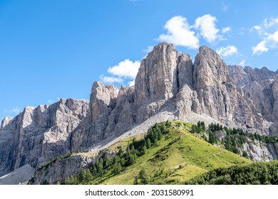 Beautiful summer mountain view of Passo Sella and high peak Sassopiatto and Sassolungo, Langkofel, Dolomiti, Sella group. Green meadows and pastures, alpine dolomites peaks and blue sky