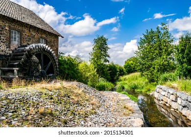 Beautiful Summer Rustic Countryside Landscape With A Water Mill And An Old Stone House. Tourist Attractions And Nature In Limburg. Artistic Landscape With A Farmhouse And A River Against The Blue Sky.