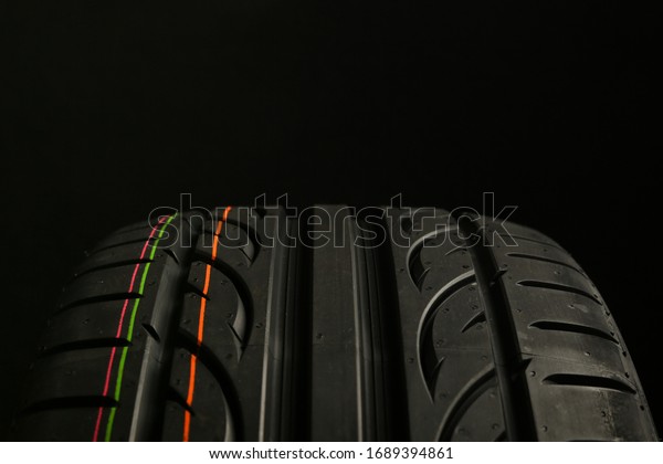 beautiful summer tire tread\
close up on black background. tread of tire with directional\
rotation close up