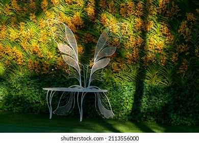Beautiful sun light and shade in vertical flower garden with white chair in front, gardening design concept, wall paper or copy space background