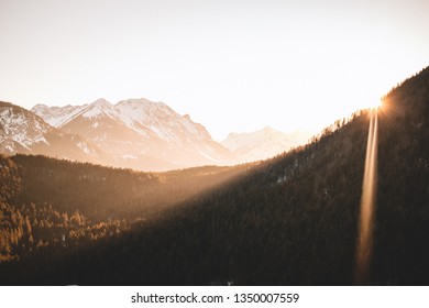Beautiful sunlight bursting through mountains sun flare snowy and green mountain background sunset