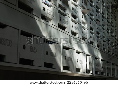Beautiful sunlight shine on rows of white wooden mailboxes with keyholes for resident in condominium or apartment. Postbox in condo, Light and shadow, Selective focus.
