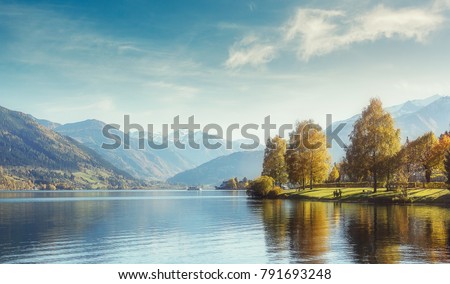 Beautiful Sunny day in Alps. wonderlust view of highland lake With autumn trees under sunlight and perfect sky. Landscape with Alps and Zeller See in Zell am See, Salzburger Land, Austria