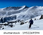 Beautiful sunny day at Breckenridge ski resort, Colorado - skier going down trail