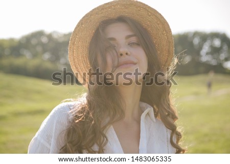 Beautiful sunny woman portrait in straw hat. Green nature on background