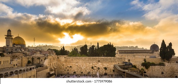 Beautiful sunrise clouds over the Mount of Olives and the Temple Mount sites: Dome of the Rock, Western Wall and Al Aqsa Mosque; with Jewish people praying in sections because of covid-19 regulations 