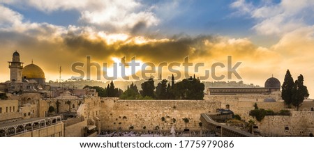 Beautiful sunrise clouds over the Mount of Olives and the Temple Mount sites: Dome of the Rock, Western Wall and Al Aqsa Mosque; with Jewish people praying in sections because of covid-19 regulations 
