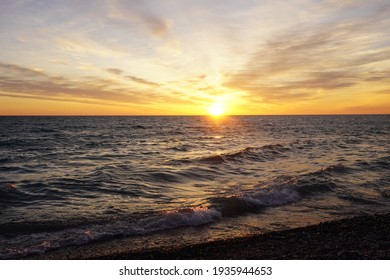 A beautiful sunrise on a lake from a rocky beach.