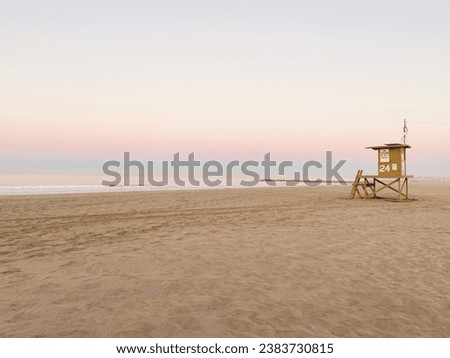 Beautiful sunrise on sandy beach with lifeguard tower. Newport Beach California.