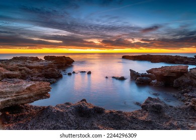 Beautiful sunrise over rocks at the beach at Torre de la Sal in the Castellon province of Valencia in Spain - Shutterstock ID 2244296309