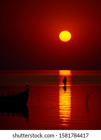 Beautiful Sunrise Over Water And Silhouette Of Old Woman Fishing